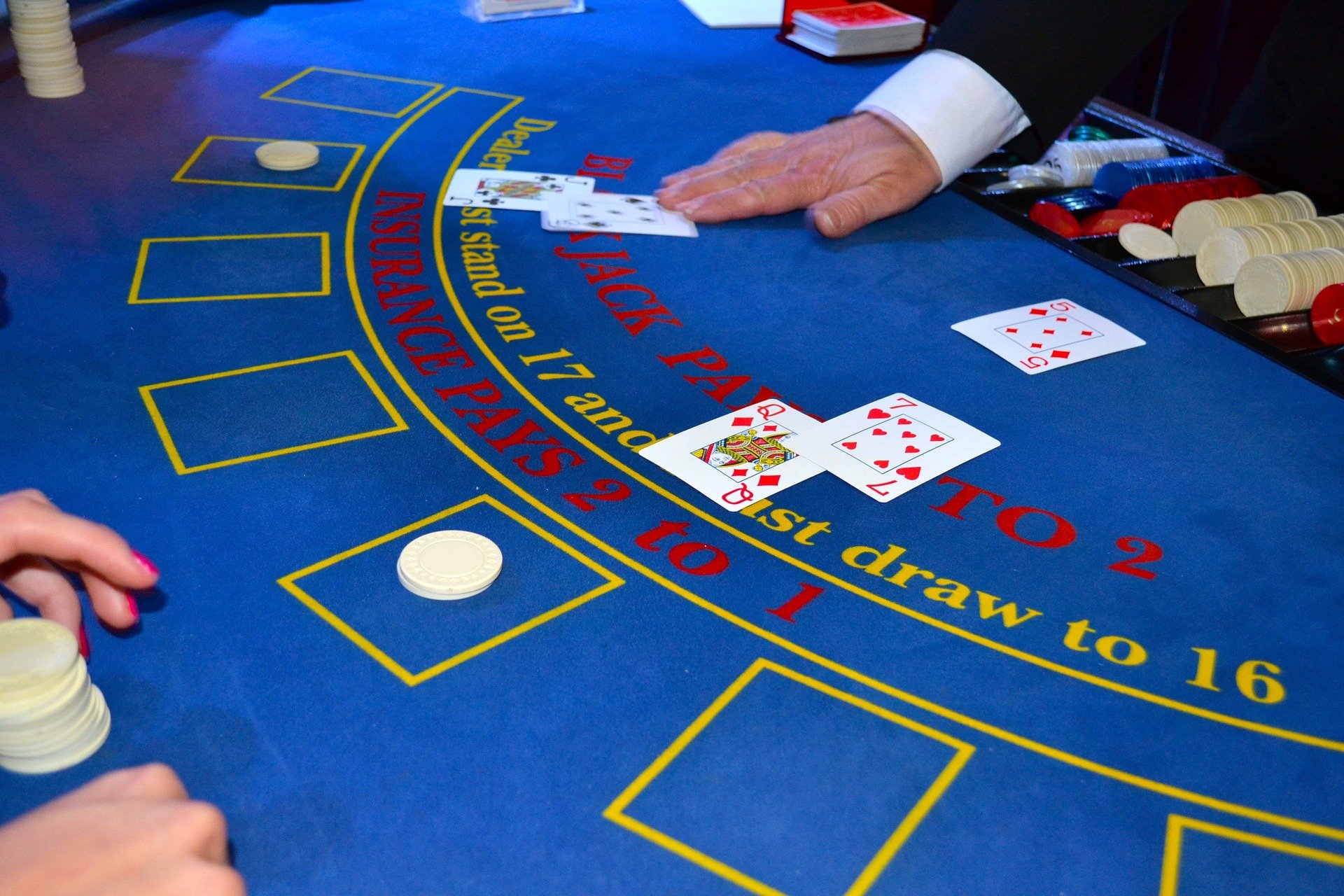 Spielsituation am Black Jack Tisch im Casino mit Dealer und Spieler und Spielkarten.