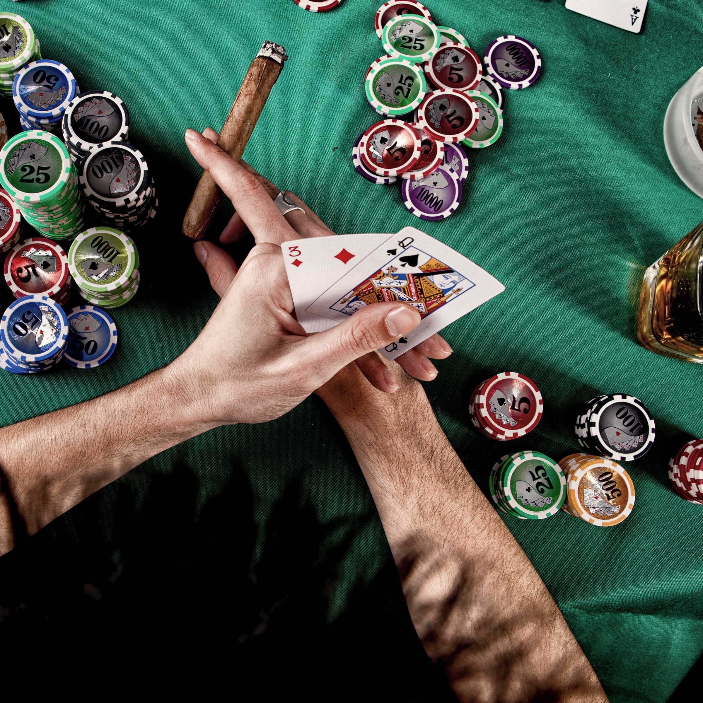 Spielsituation am Poker Tisch mit zwei Handkarten und Spielchips