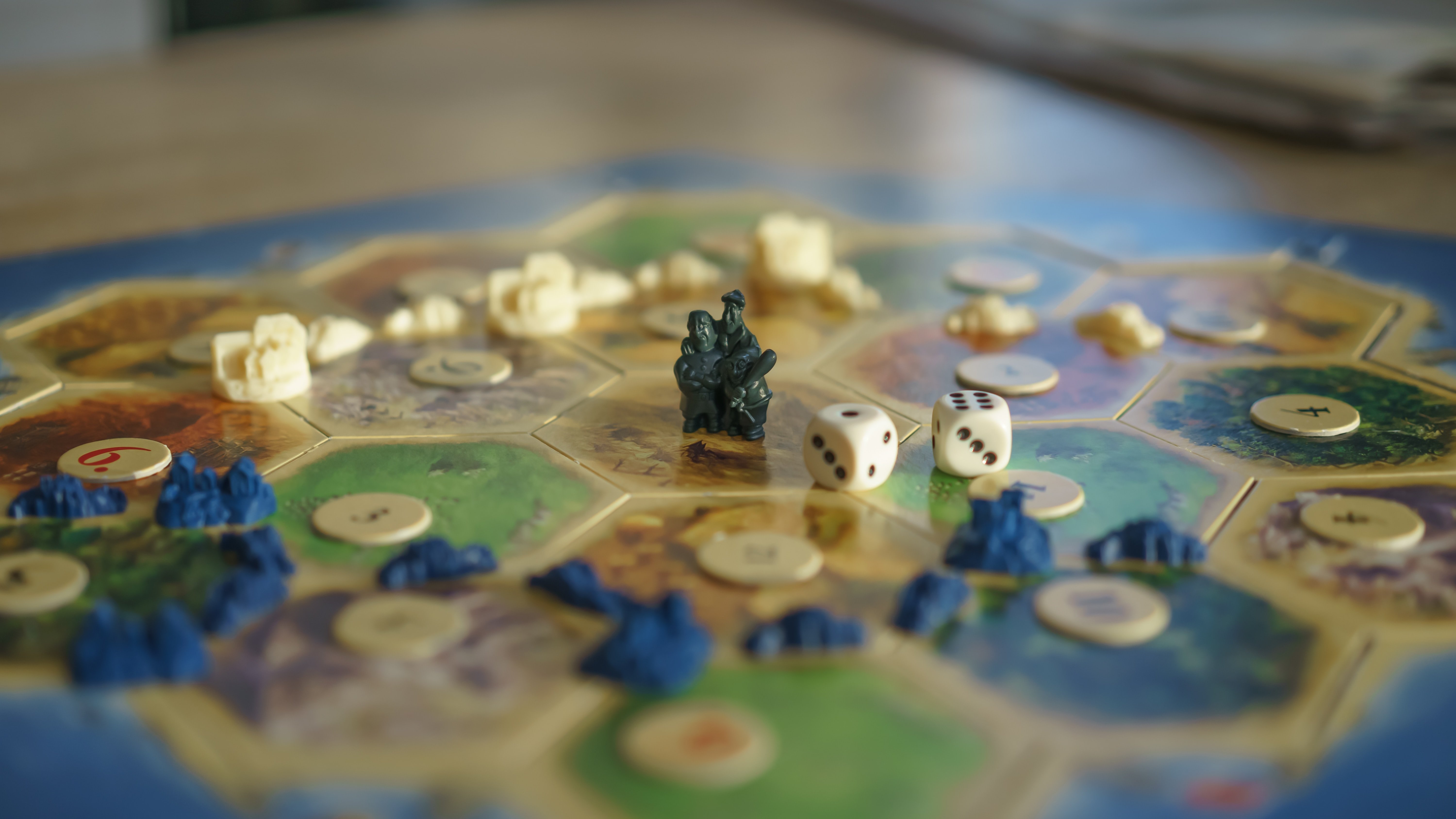 Foto: Nahaufnahme des Spielbretts mit Würfeln und Spielsteinen bei Catan.