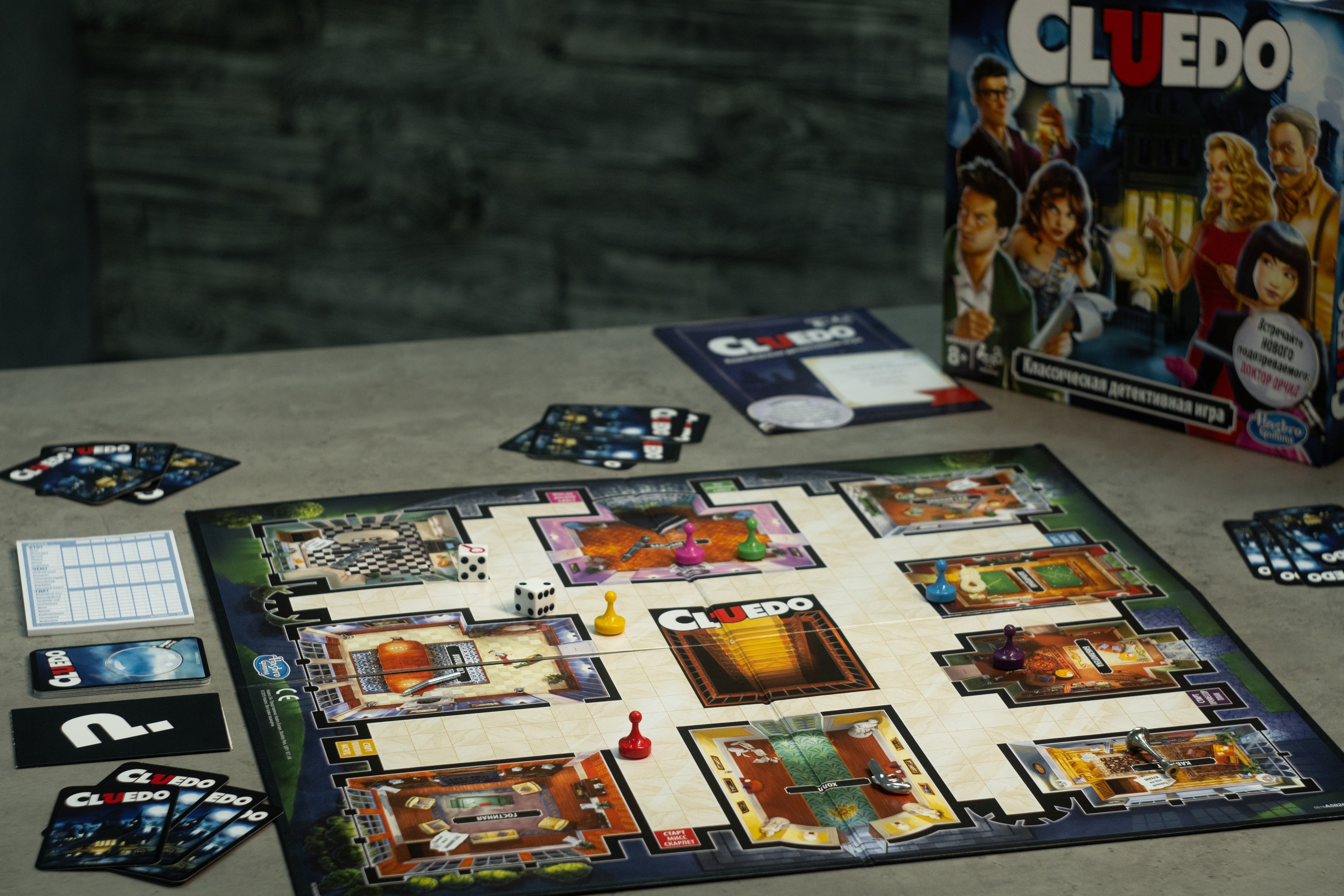 Foto: Aufsicht auf ein Spielbrett des Detektivspiels Cluedo mit Karten und Spielsteinen.