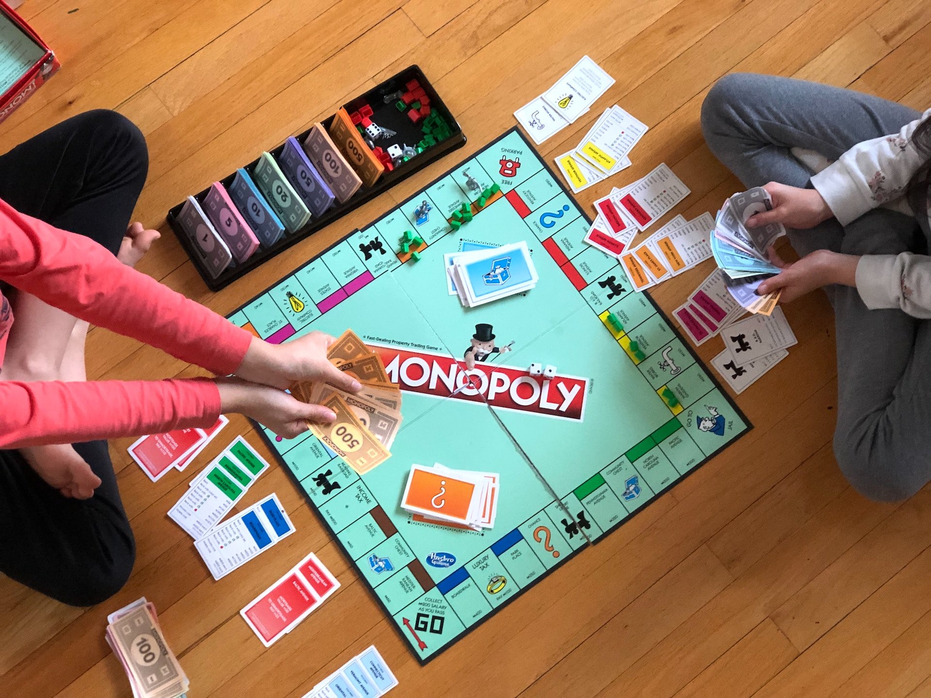 Foto: Aufsicht auf ein aufgebautes Monopoly Spielbrett mit Spielkarten, Spielsteinen und zwei Spielern.