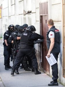 Beamte der Finanzpolizei brechen eine Tür auf