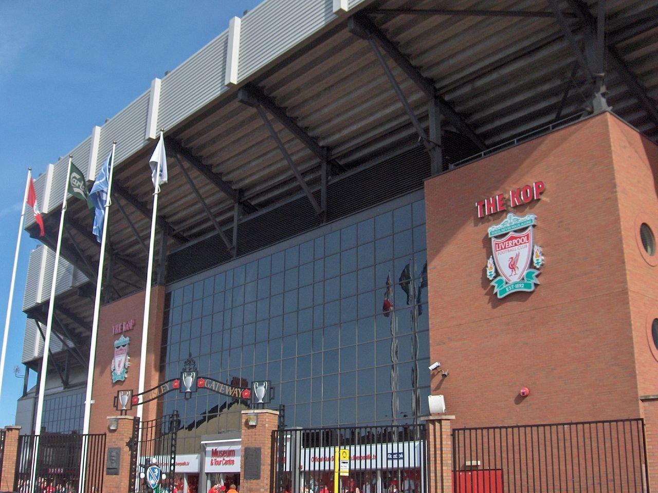 Anfield Road Stadion mit Flaggen und FC Liverpool-Wappen||Tom Watson Portrait|Wappen des FC Liverpool