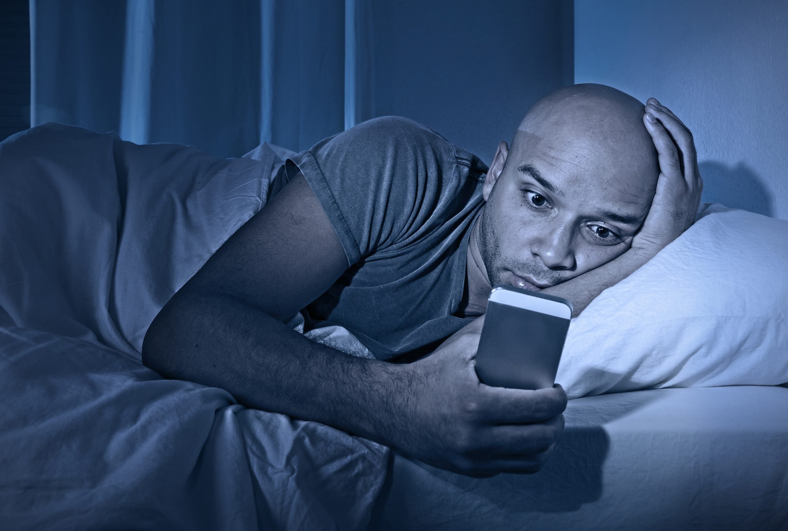 Mann mit Smartphone im Bett||