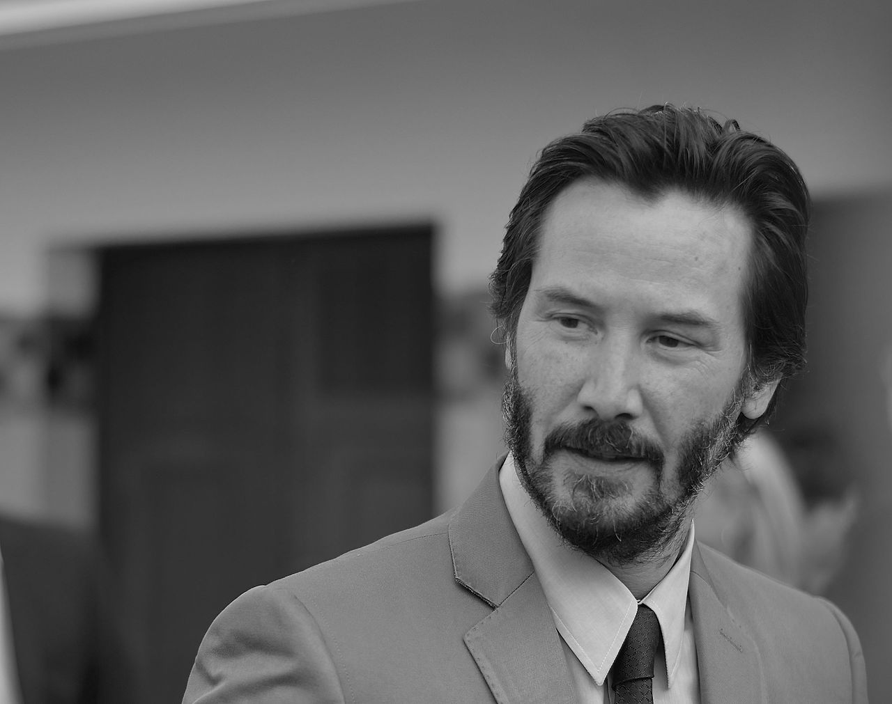 Keanu Reeves in Anzug mit Bart|Das Logo der E3||