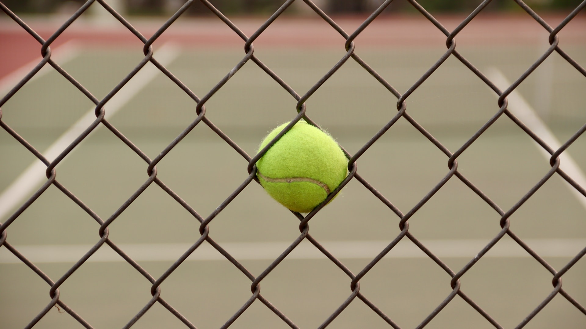 Tennisball klemmt in Zaun