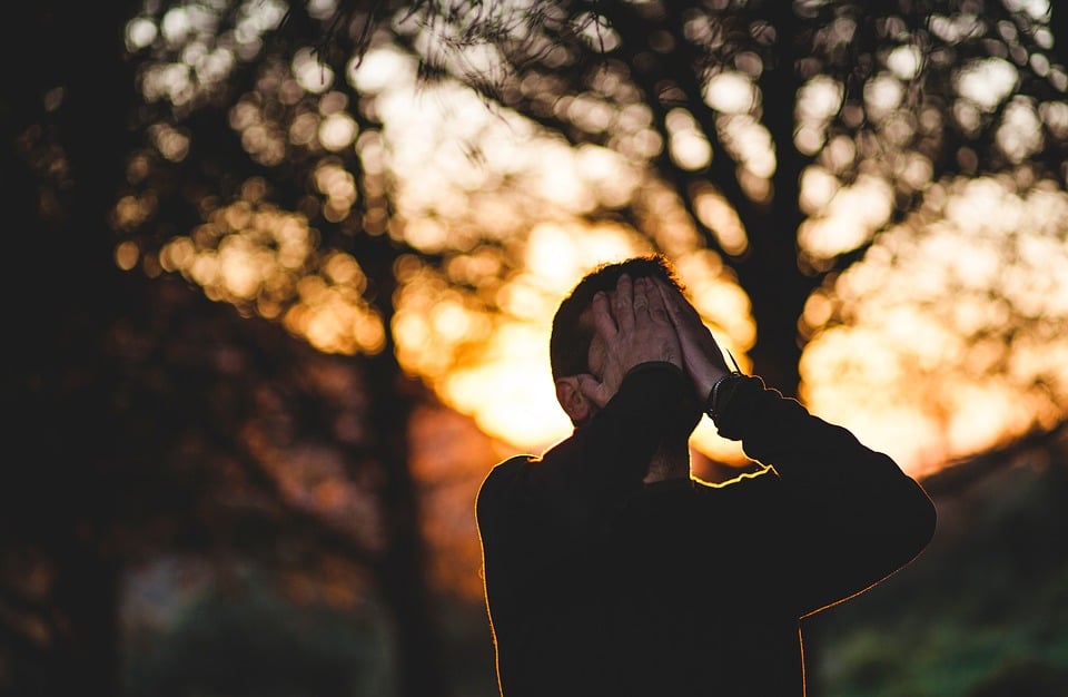 Mann mit Händen im Gesicht draußen Sonnenuntergang