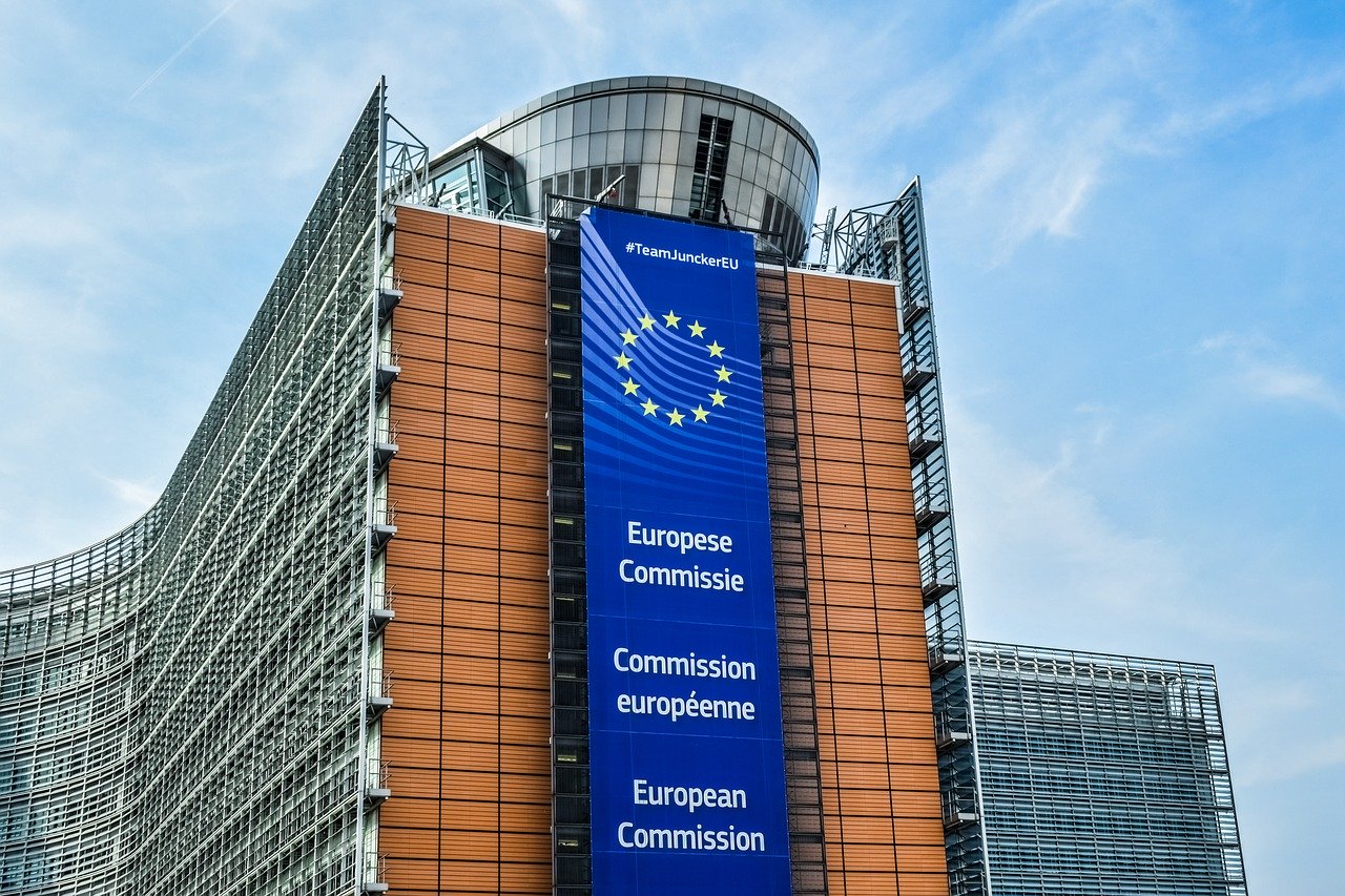 Gebäude der Europäischen Kommission|Lupe auf Paragraphenzeichen mit Wage als Symbole für Recht und Gesetz
