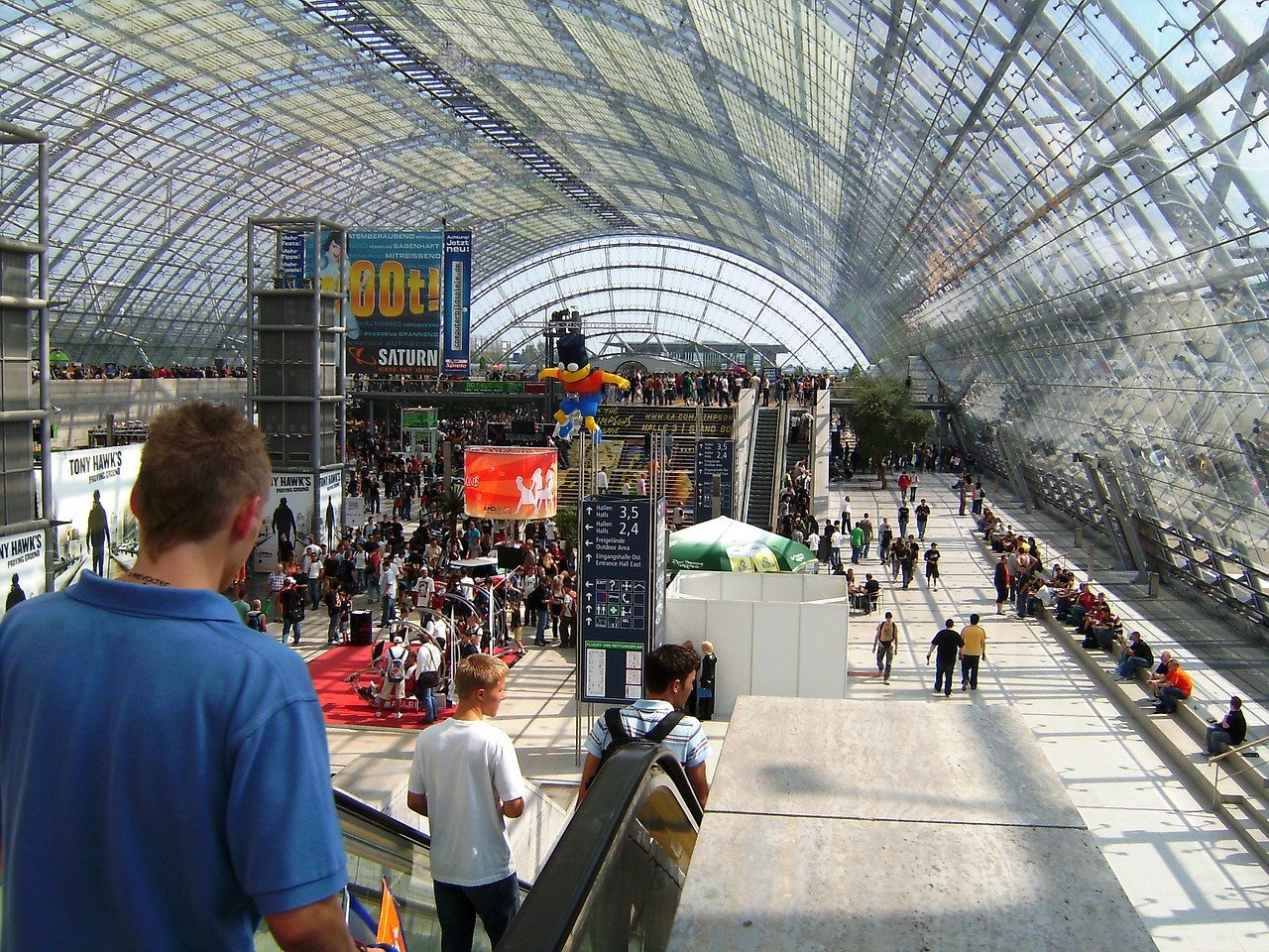 Besucher in einer Messehalle|Ein Computer mit Lupe und Geld