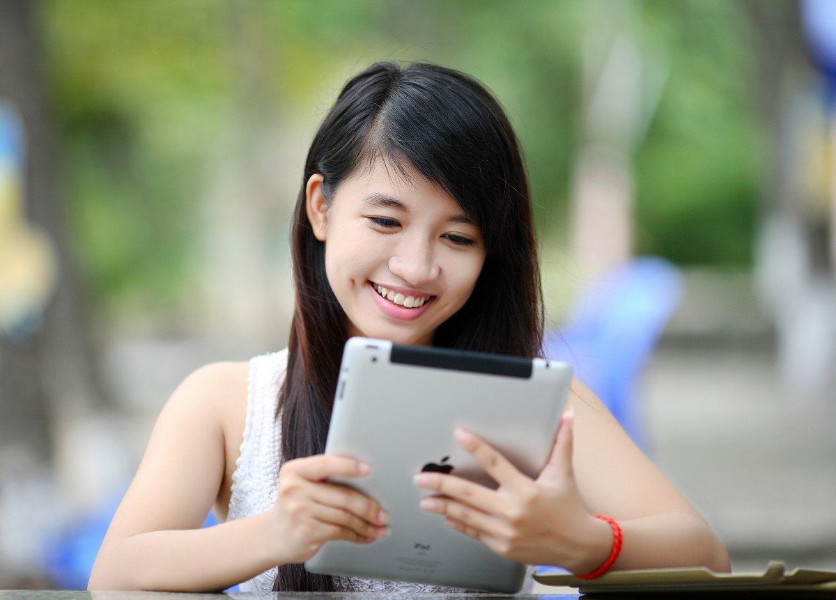 Asiatisches Mädchen mit iPad draußen