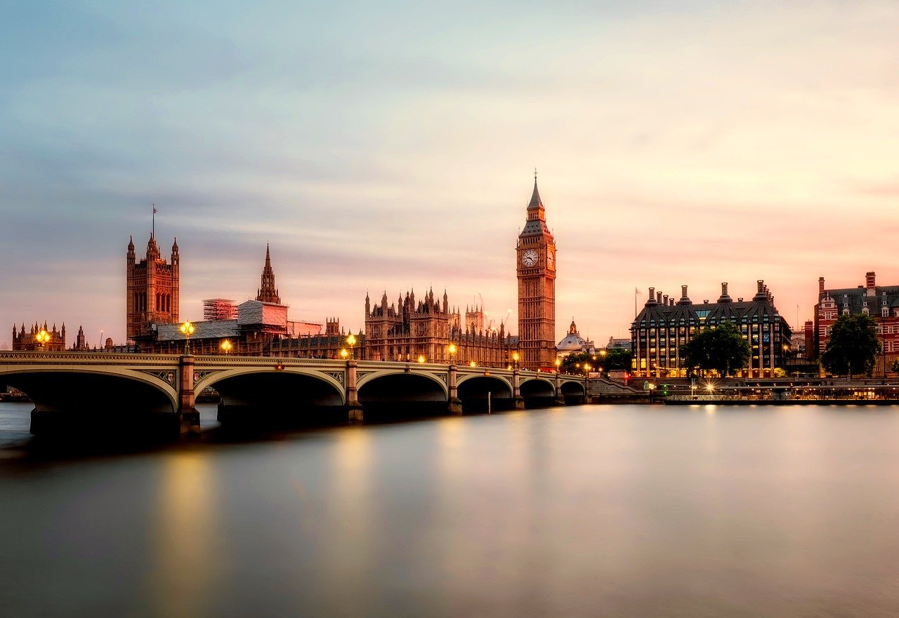 Das Parlament und die Themse in London|Das britische Parlament und die Themse|Mann hinter einem Eisentor|Das Logo der NHS