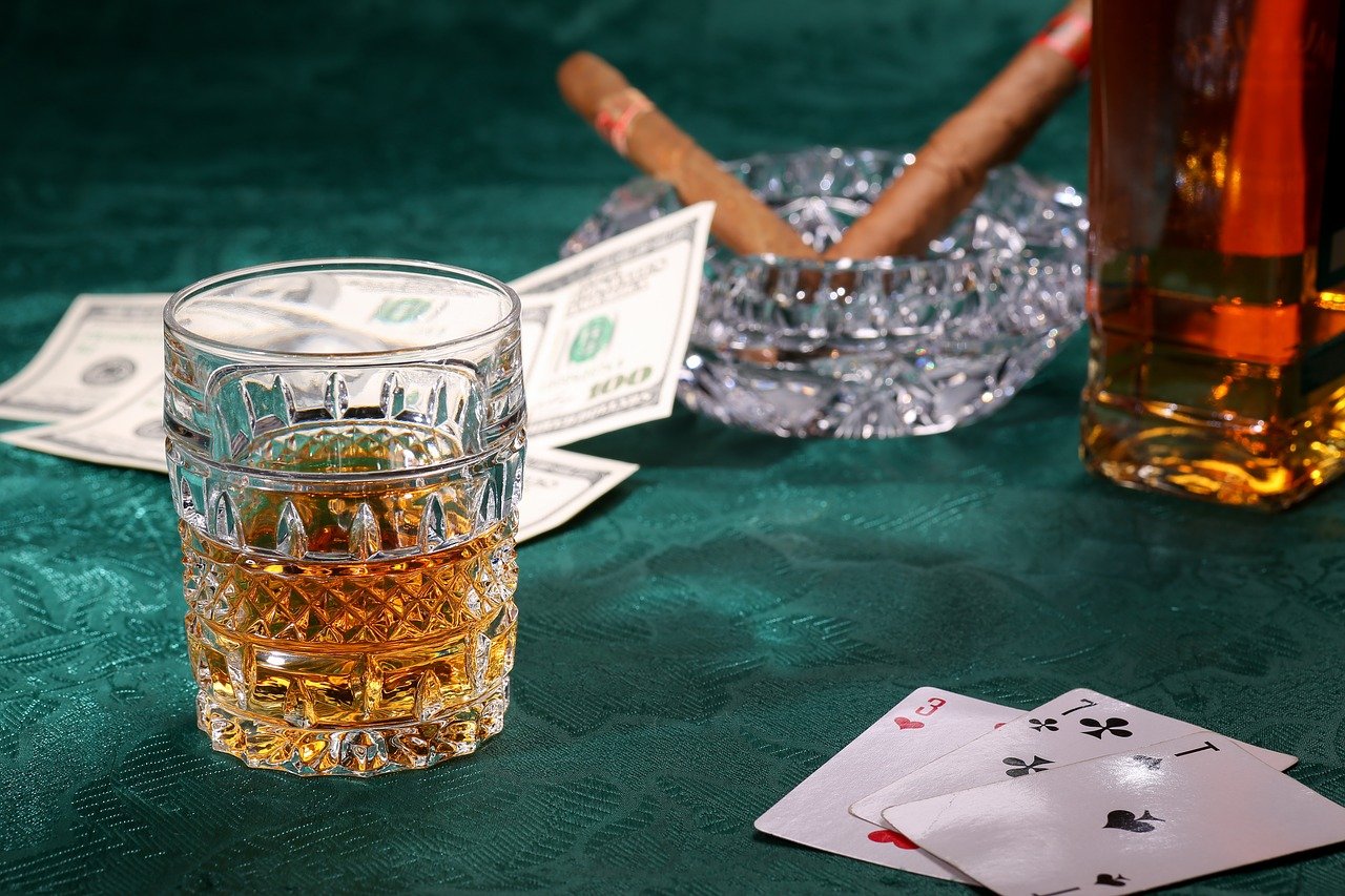 Whisky im Glas neben Spielkarten Geld und Zigarren|roulette|Mann trinkt Alkohol aus Flasche|Mann trinkt Alkohol aus Flasche|Geld und Spielkarten