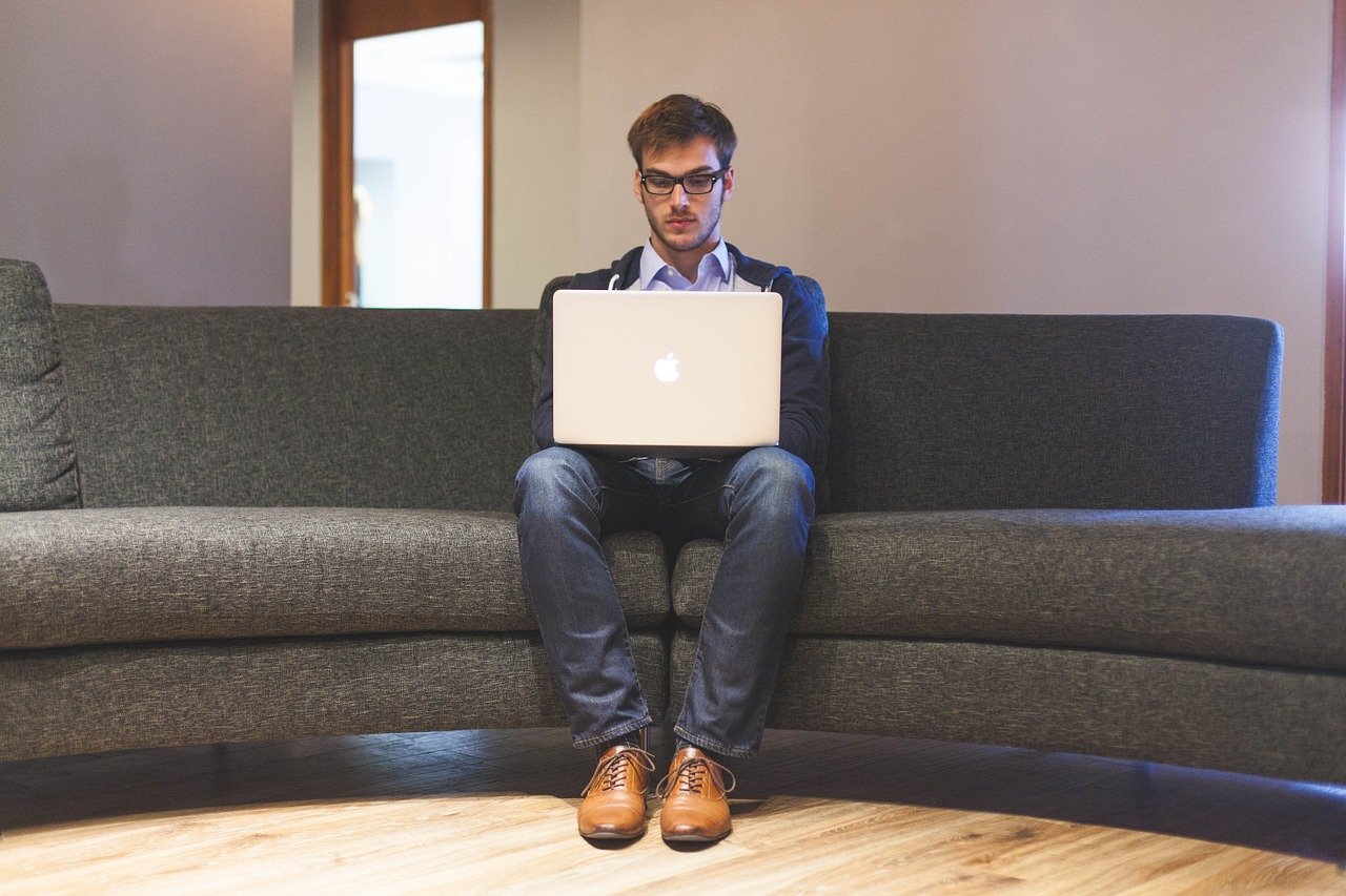 Mann am Laptop auf Sofa