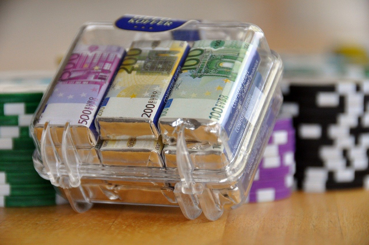 Euro Geldscheine in durchsichtigem Koffer Casino Chips|Fragezeichen auf Waage