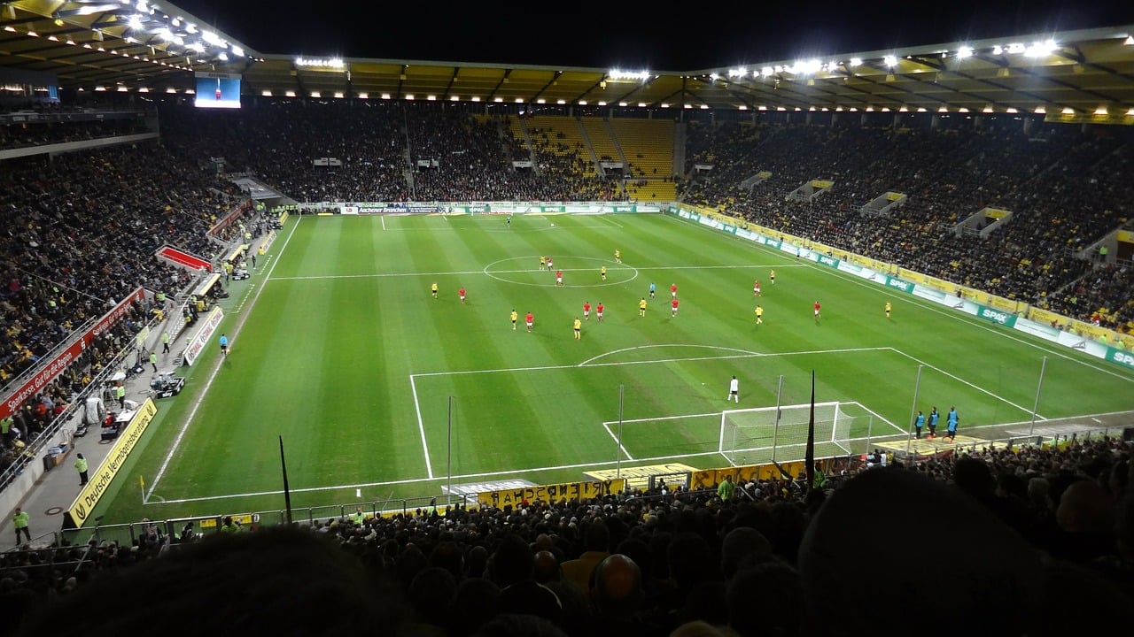 Ein Fußballstadion bei einem Spiel|Ein Tennisstadion bei Tag|Eine Kamera vor dem UEFA Logo