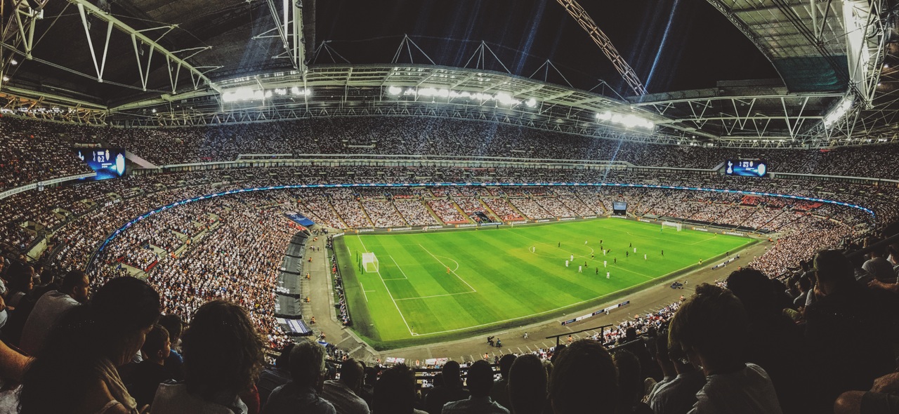 Ein Fußballstadion am Abend|Eine Kamera am Spielfeldrand