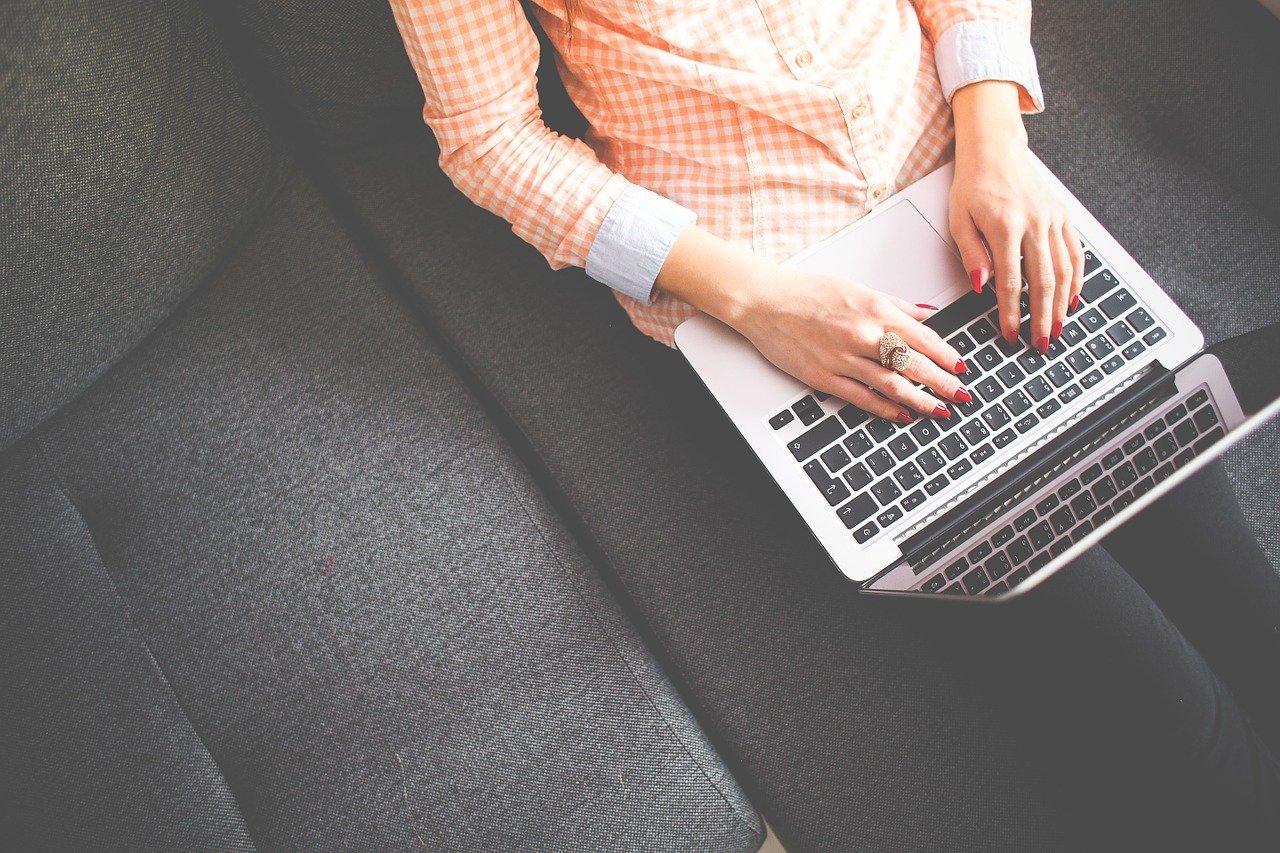 Person am Laptop auf Couch Hände Tastatur