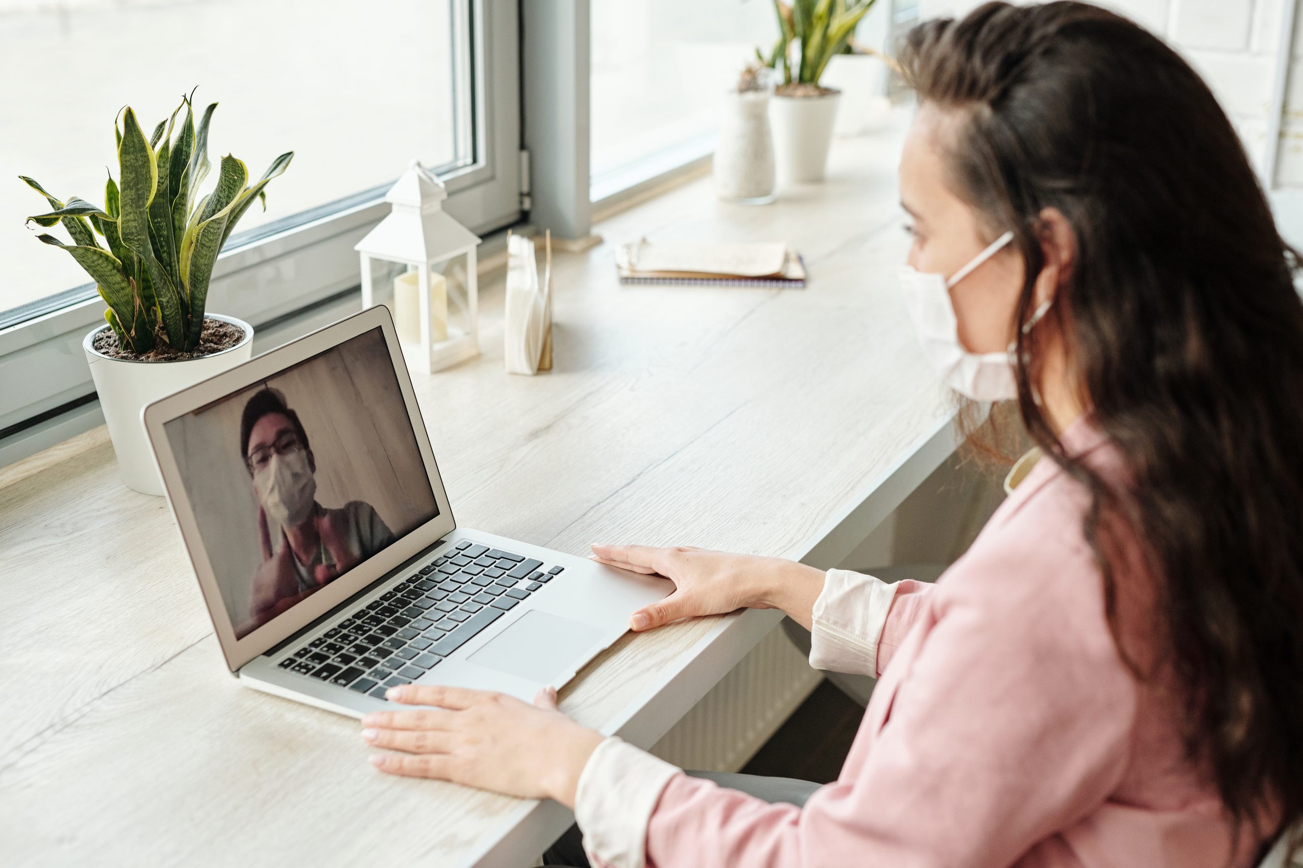 Frau am Laptop im Video-Anruf mit Schutzmaske