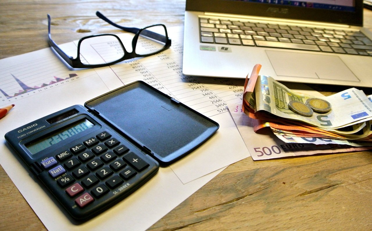 Ein Tisch mit Rechner und Geld|Wettbüro an einer Straße||Ein Sack mit Geldscheinen|