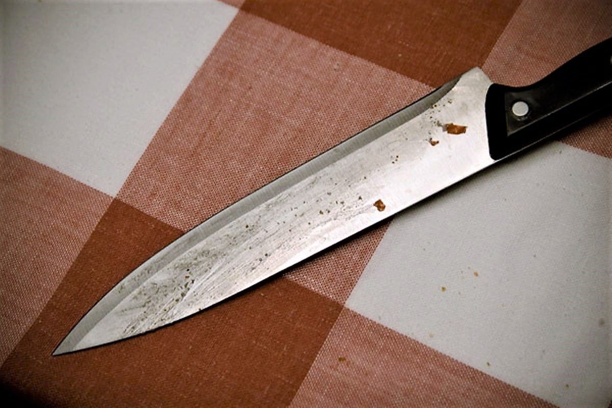 Blutiges Messer auf karierter Tischdecke