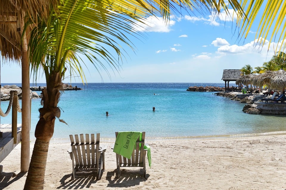 Curaçao Palme Liegestühle am Strand seichtes Wasser Meer Karibik