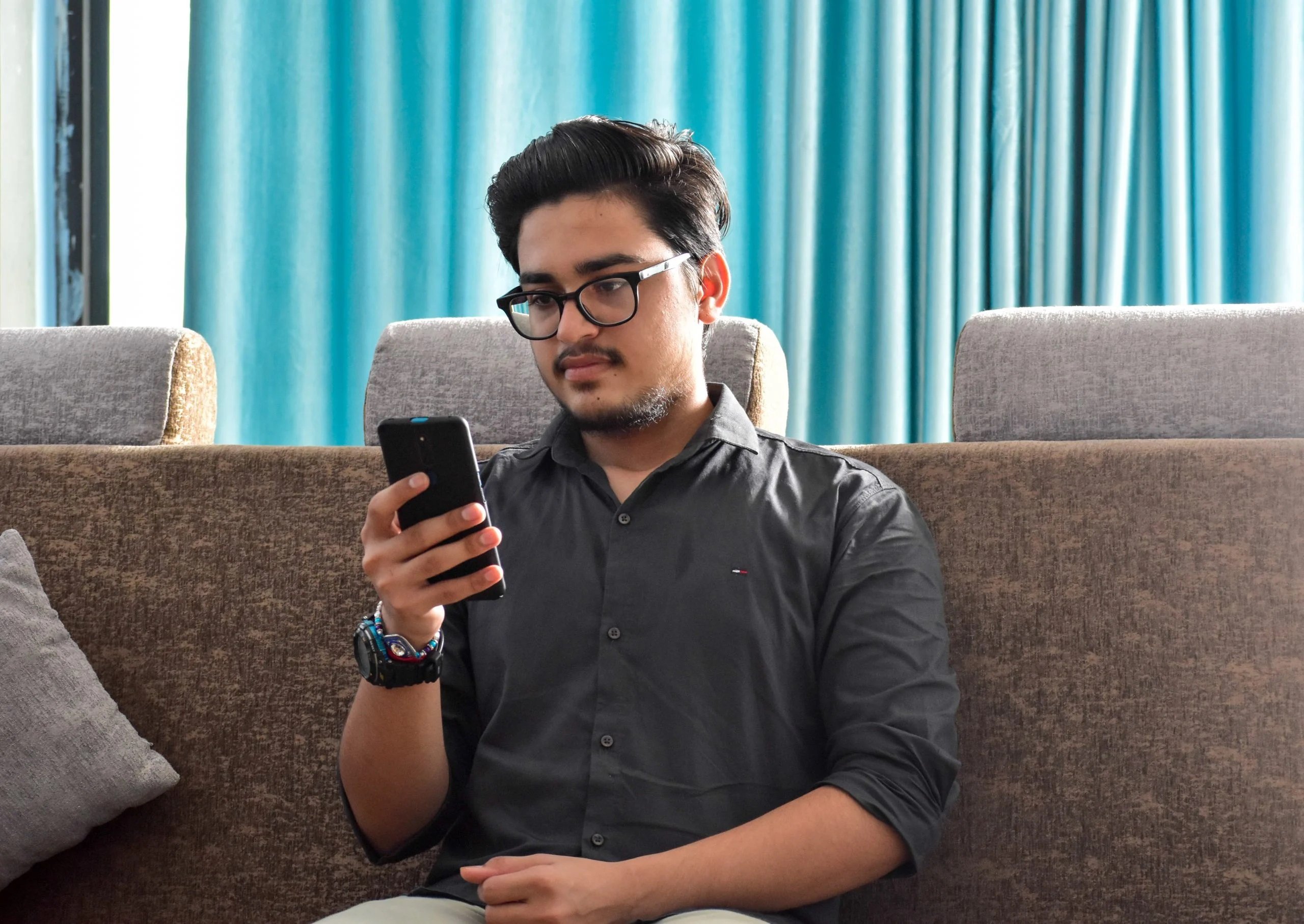 Mann mit Smartphone in der rechten Hand auf Sofa