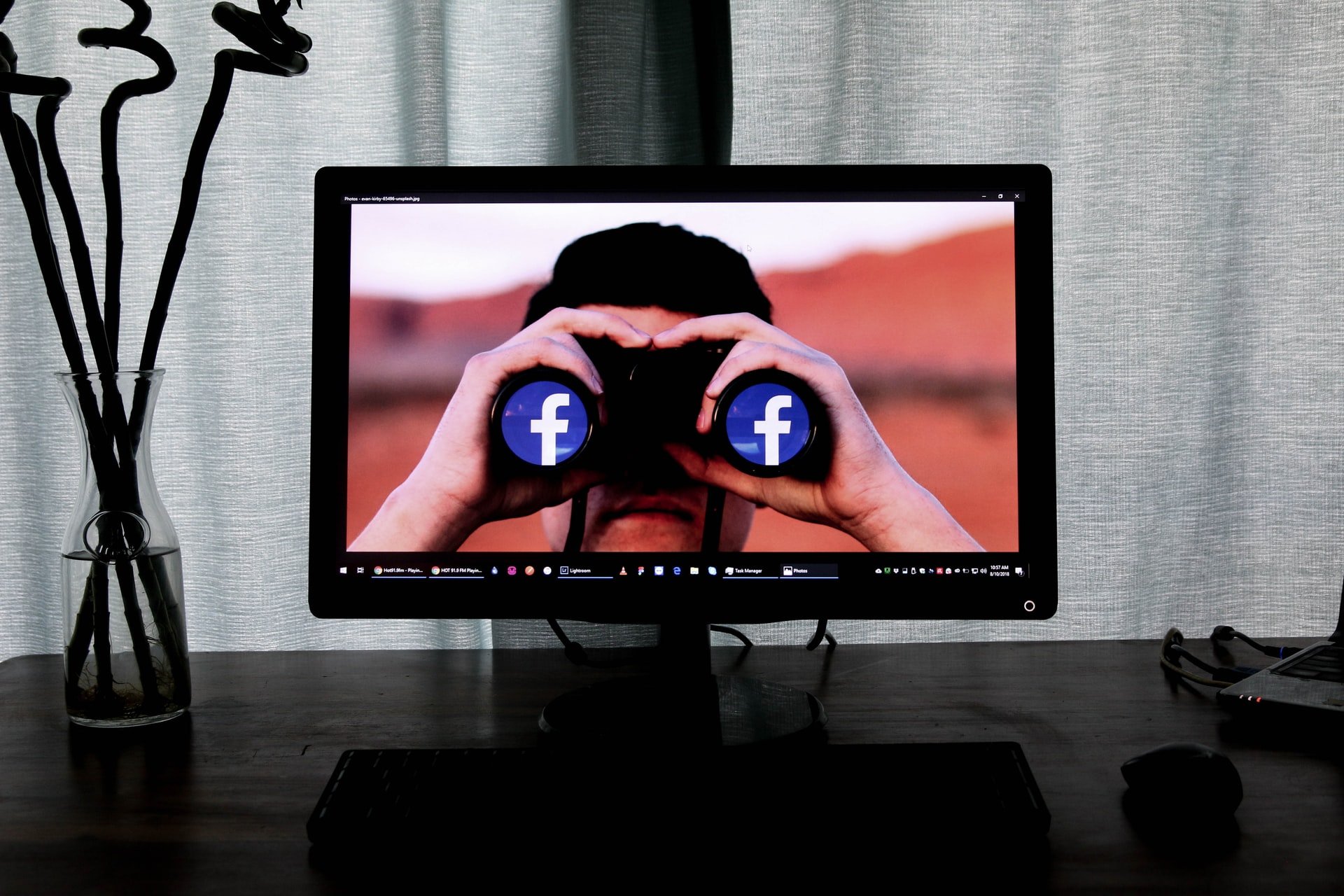 Computermonitor Mann schaut durch Fernglas mit Facebooklogo