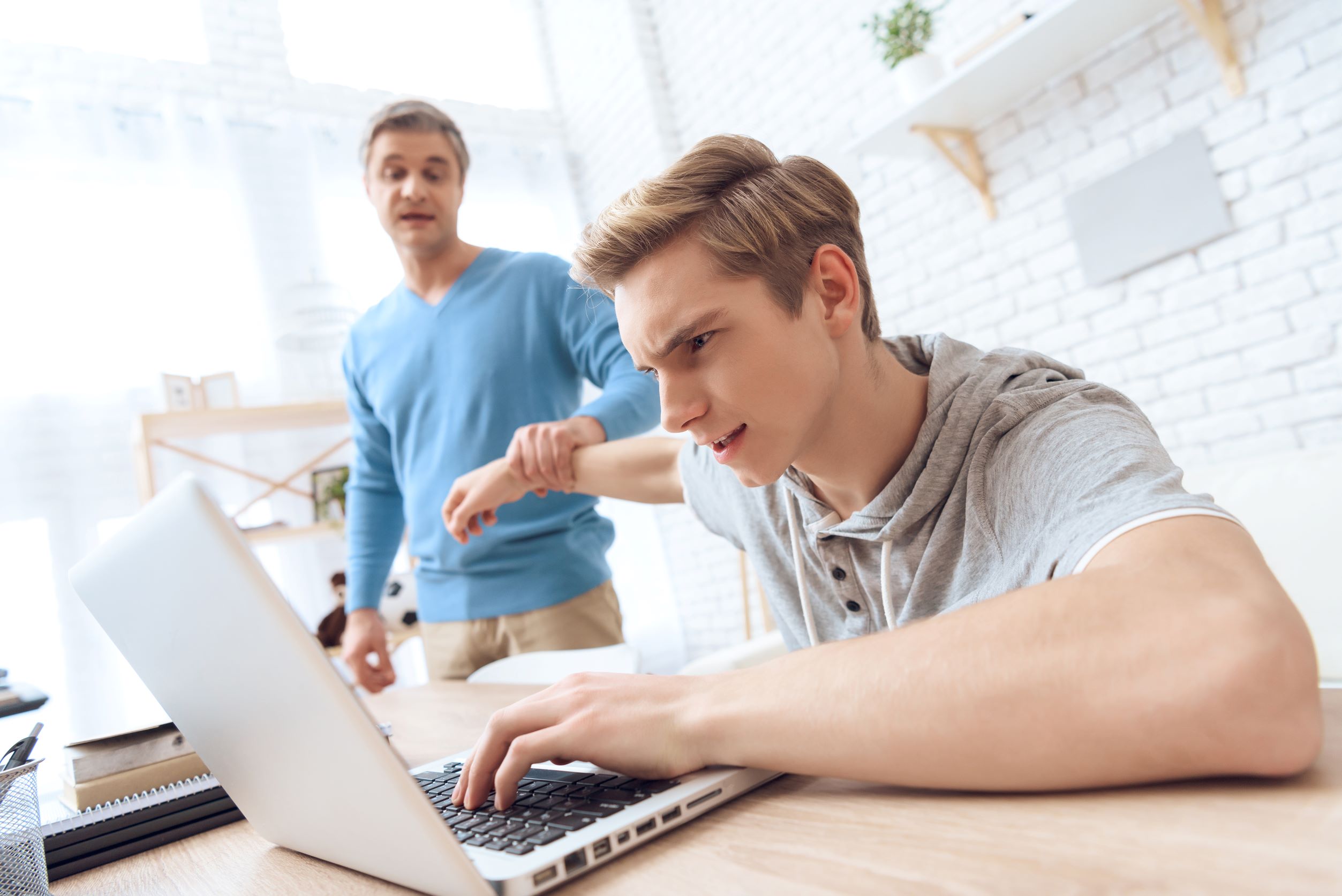 Teenager am Computer Laptop älterer Mann im Hintergrund