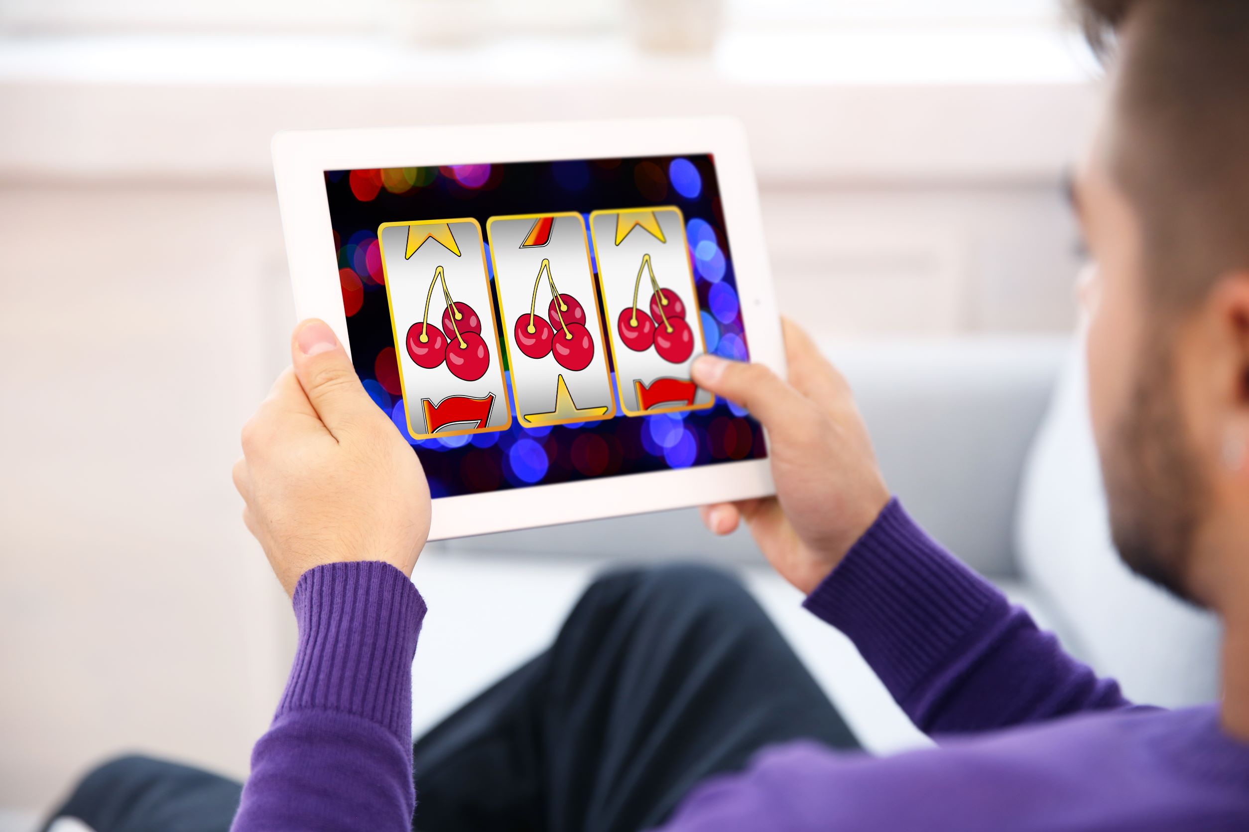 Mann spielt Online-Slot Fruit Machine auf Tablet
