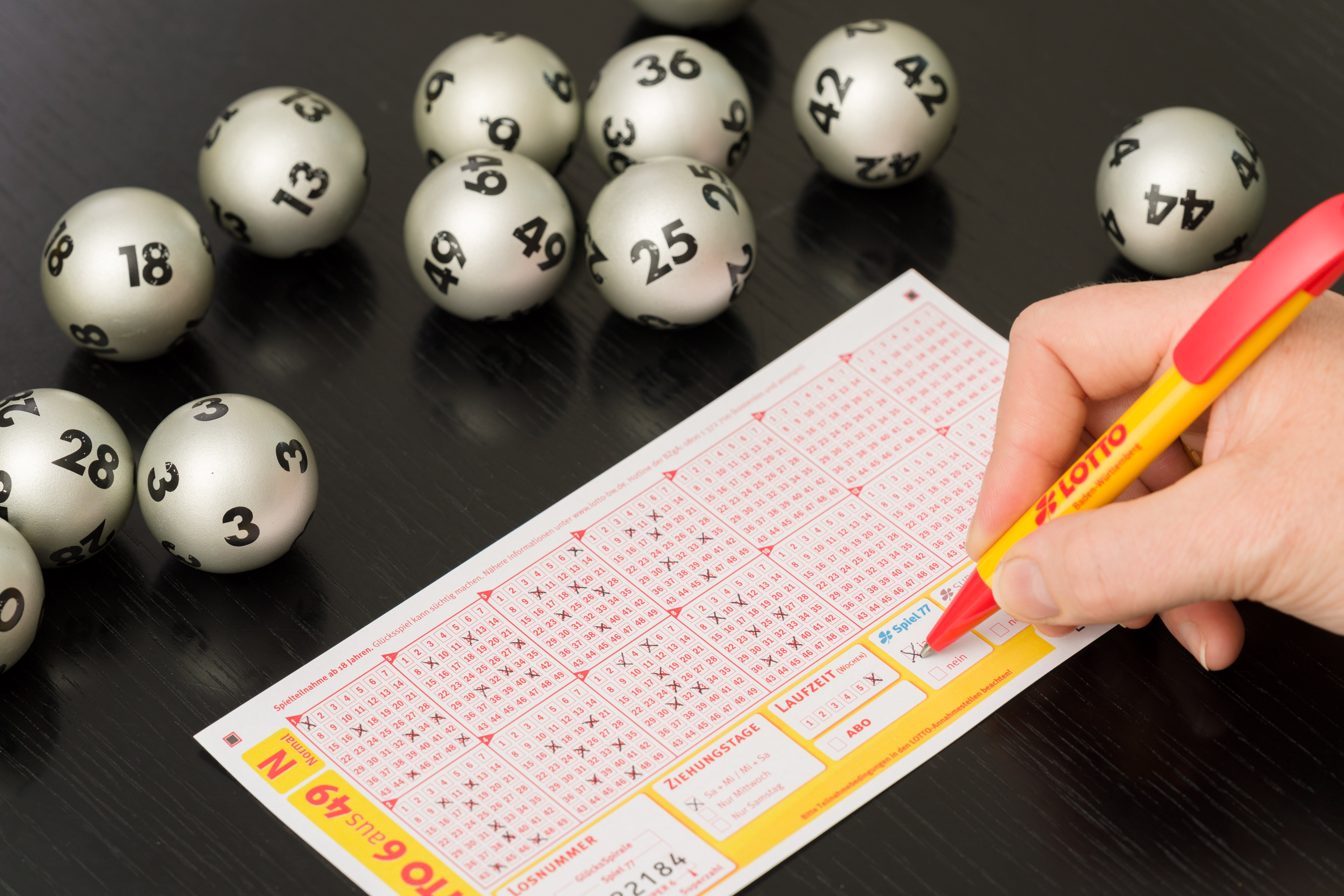 Deutscher Lottoschein Hand mit Strift silberne Lottokugeln