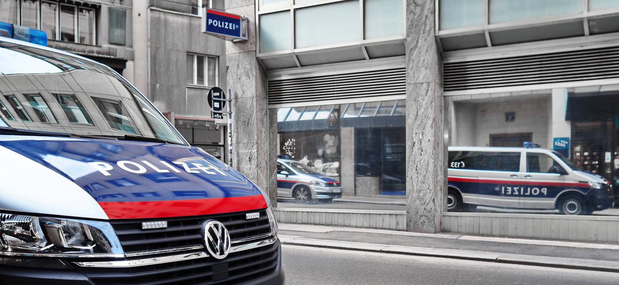 Österreich Polizeifahrzeuge spiegeln sich in Fensterscheibe